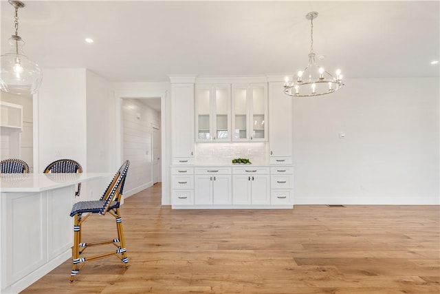 interior space featuring an inviting chandelier, light hardwood / wood-style floors, hanging light fixtures, and white cabinets