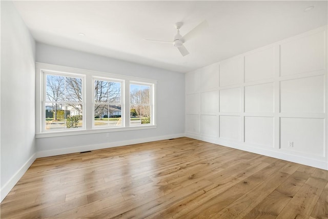 unfurnished room featuring ceiling fan, a wealth of natural light, and light wood-type flooring