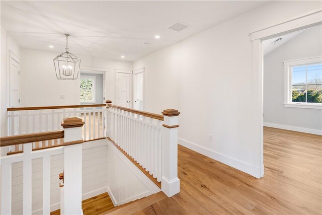 stairway featuring a notable chandelier, wood-type flooring, and vaulted ceiling