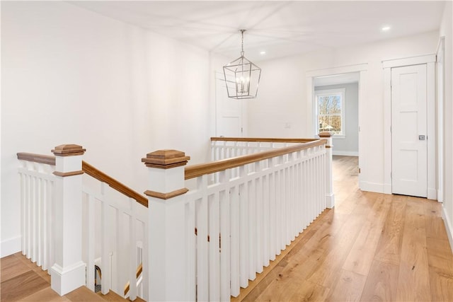 hallway with an inviting chandelier and light hardwood / wood-style flooring