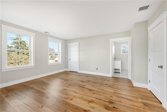 unfurnished bedroom featuring ensuite bathroom and light hardwood / wood-style floors