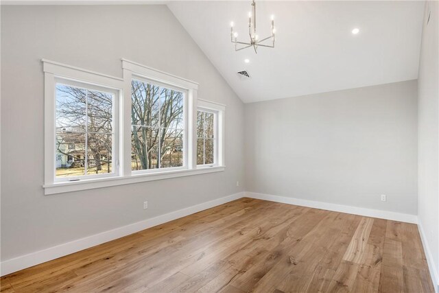 additional living space featuring wood-type flooring, lofted ceiling, and an inviting chandelier