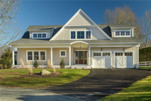 view of front facade with covered porch, a garage, and a front yard