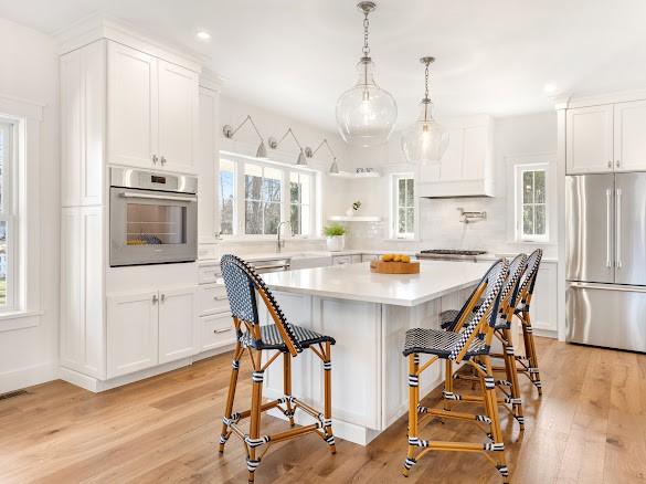 kitchen with decorative light fixtures, white cabinetry, a kitchen bar, a center island, and stainless steel appliances