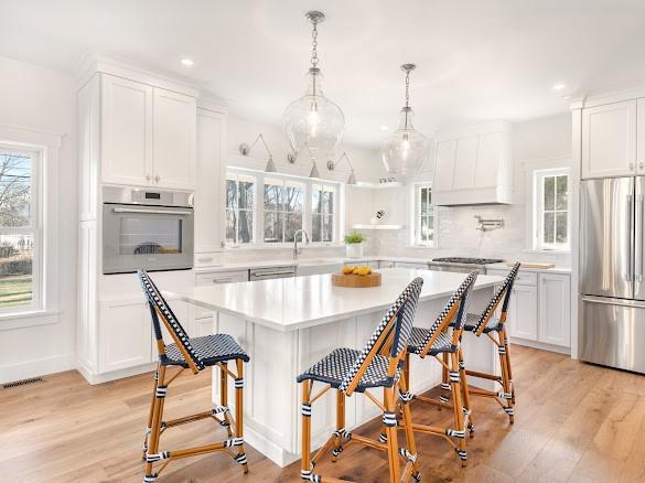 kitchen with a kitchen island, a breakfast bar, decorative light fixtures, white cabinetry, and stainless steel appliances