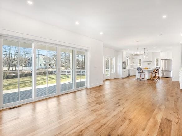 unfurnished living room with light hardwood / wood-style floors and a chandelier