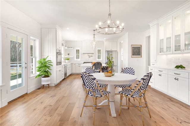 dining space with french doors, a chandelier, light hardwood / wood-style floors, and a wealth of natural light