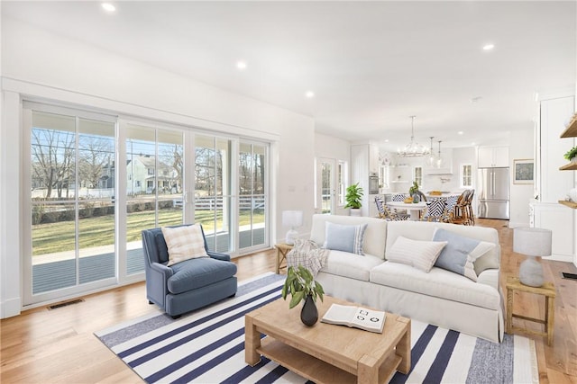 living room featuring a notable chandelier and light wood-type flooring