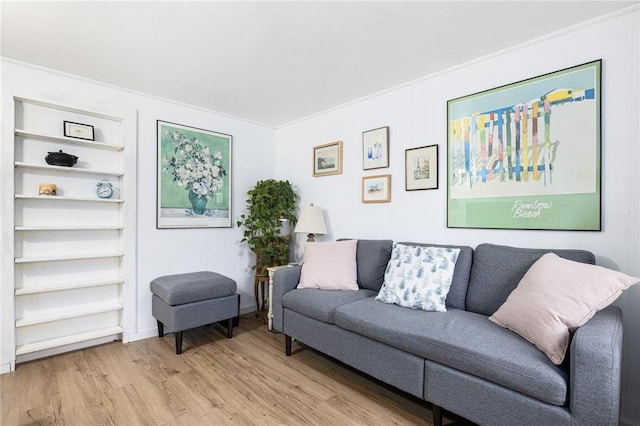 living room with light wood-type flooring and ornamental molding