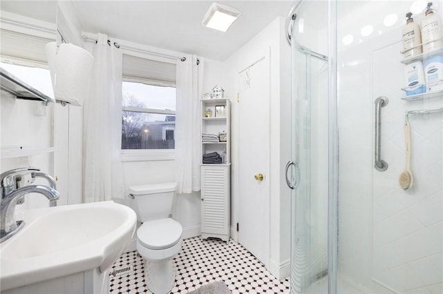 bathroom with toilet, a shower with door, and sink