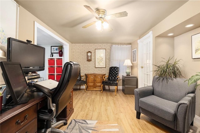 office area with ceiling fan, light hardwood / wood-style floors, and brick wall