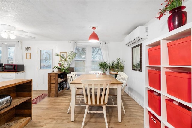 dining room featuring a textured ceiling, light hardwood / wood-style floors, a wall mounted AC, and ceiling fan