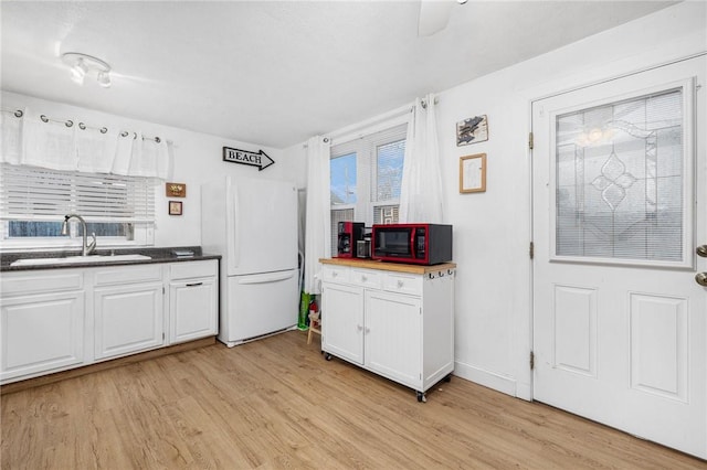 kitchen with white cabinetry, sink, white fridge, and light hardwood / wood-style floors