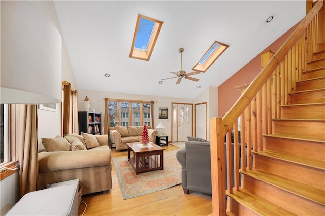 living room with ceiling fan, light hardwood / wood-style floors, high vaulted ceiling, and a skylight