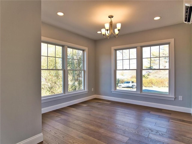 unfurnished room featuring a notable chandelier, a healthy amount of sunlight, and wood-type flooring