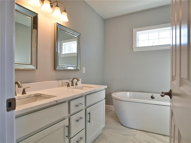 bathroom with a freestanding bath, double vanity, a sink, and marble finish floor