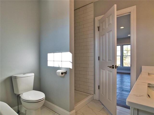 bathroom with toilet, vanity, and a tile shower