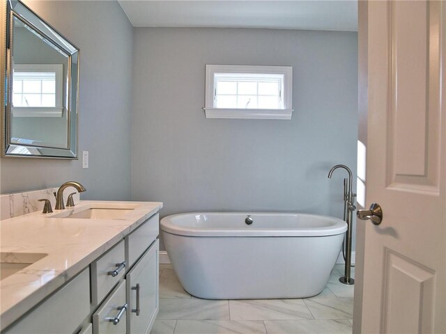 bathroom with a tub to relax in, a wealth of natural light, and vanity