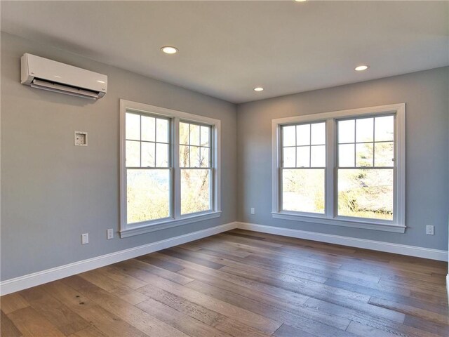 unfurnished room with hardwood / wood-style floors and a wall mounted air conditioner