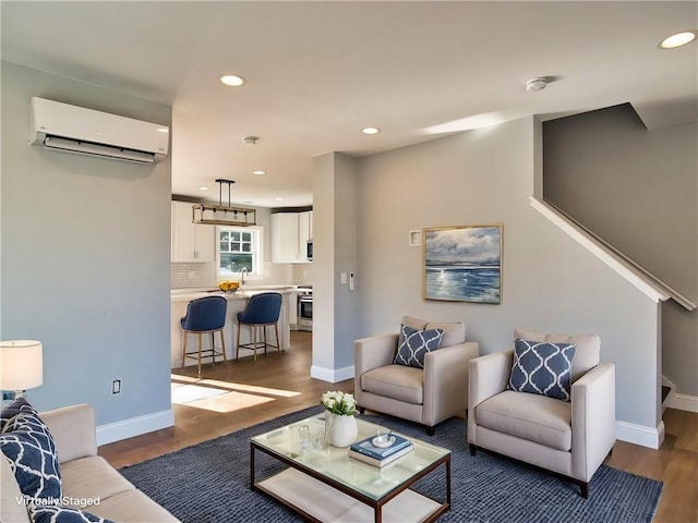 living room with an AC wall unit, dark wood-style flooring, and baseboards