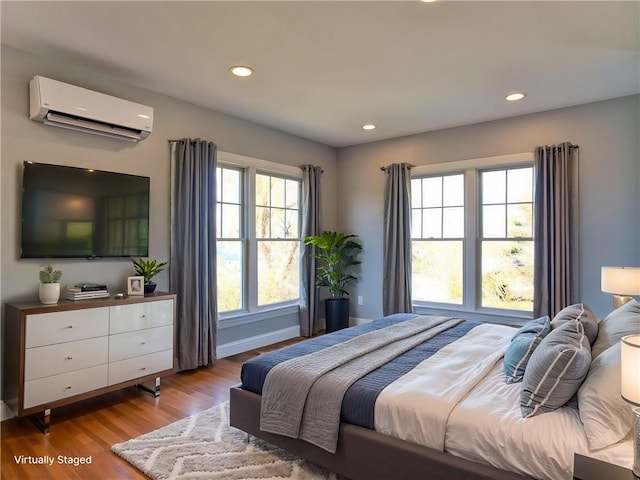 bedroom with recessed lighting, baseboards, a wall mounted air conditioner, and light wood finished floors