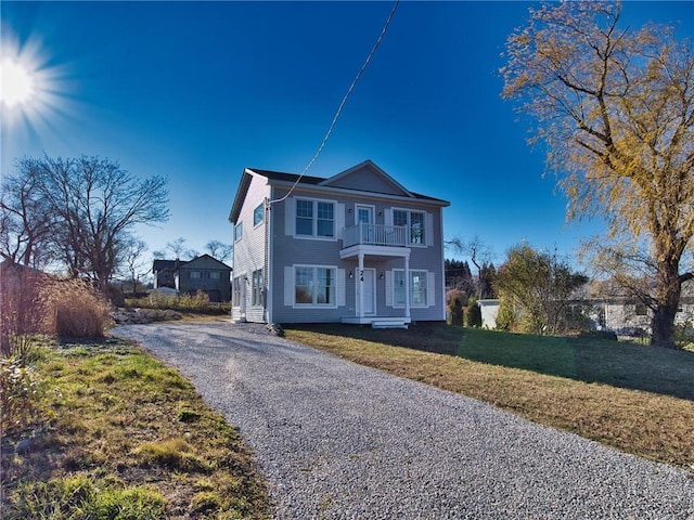 view of front of house featuring a balcony, driveway, and a front yard