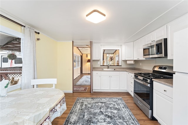 kitchen with dark hardwood / wood-style flooring, stainless steel appliances, white cabinetry, and sink