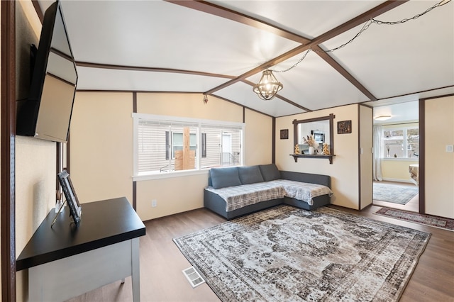 living room with hardwood / wood-style flooring, vaulted ceiling, plenty of natural light, and a notable chandelier