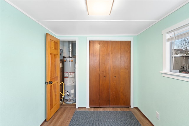 unfurnished bedroom featuring a closet, water heater, and hardwood / wood-style floors