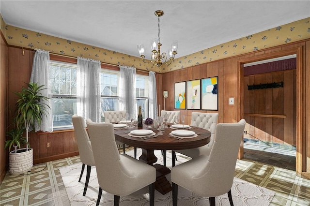 dining space featuring wooden walls and a chandelier