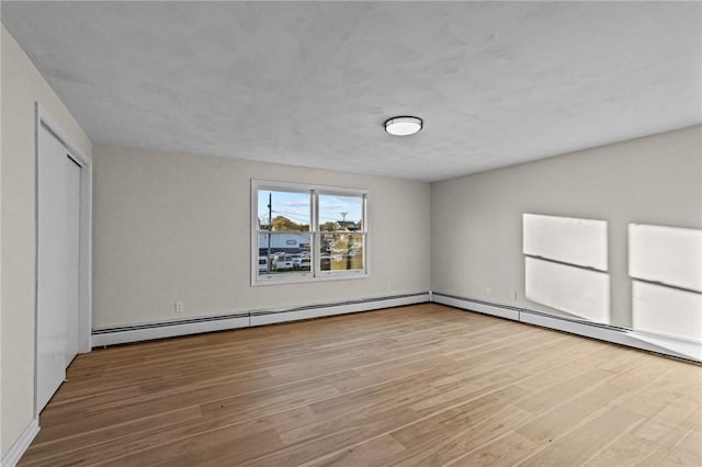 unfurnished bedroom featuring wood-type flooring and a baseboard radiator