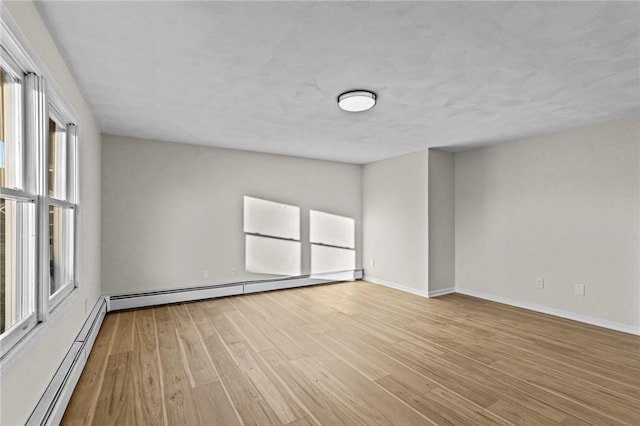 unfurnished room featuring light hardwood / wood-style flooring and a baseboard heating unit