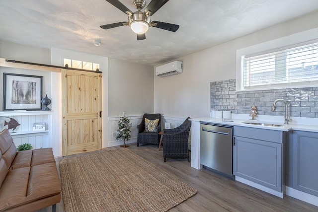 interior space featuring dishwasher, sink, a barn door, a wall unit AC, and wood-type flooring