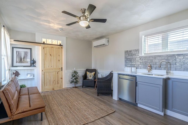 kitchen with backsplash, a wall unit AC, sink, dishwasher, and hardwood / wood-style floors