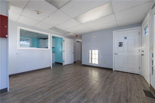 unfurnished living room featuring a drop ceiling and dark wood-type flooring