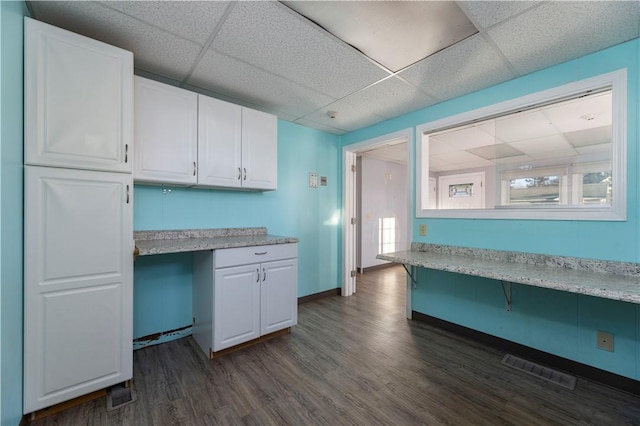 kitchen featuring built in desk, dark hardwood / wood-style flooring, white cabinetry, and a paneled ceiling