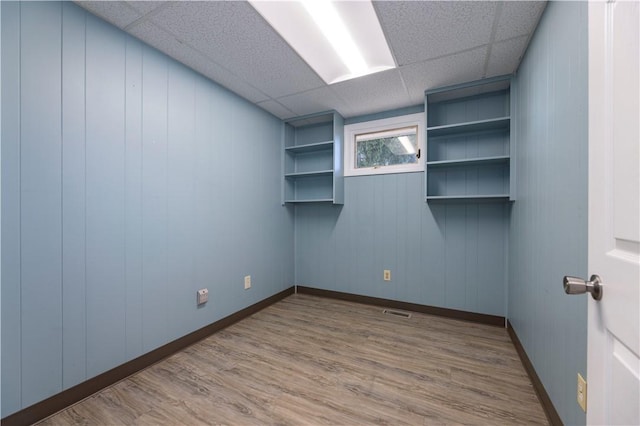 spare room featuring a paneled ceiling, hardwood / wood-style flooring, and wood walls