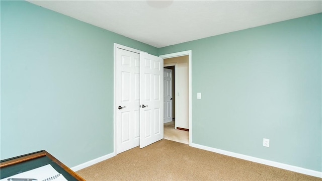 unfurnished bedroom with light colored carpet and a closet