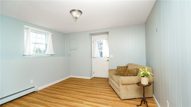 living area with a wealth of natural light, light wood-type flooring, and baseboard heating