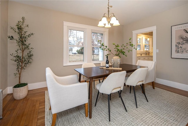 dining area with sink, light hardwood / wood-style floors, and an inviting chandelier