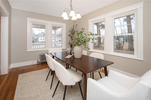 dining space featuring radiator heating unit, an inviting chandelier, and hardwood / wood-style flooring