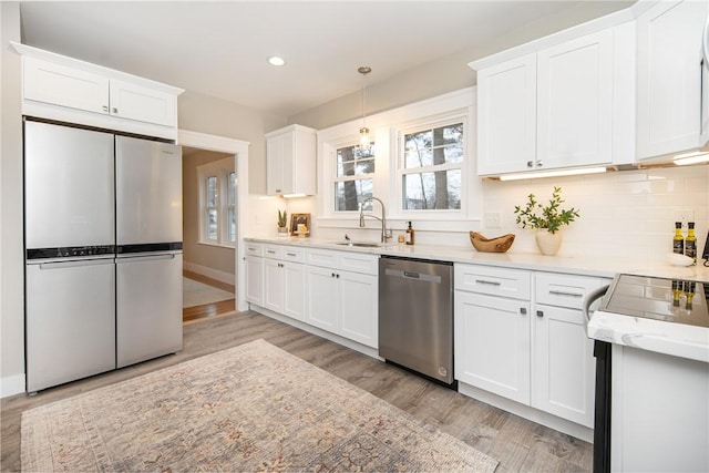 kitchen with white cabinets, light hardwood / wood-style floors, sink, and appliances with stainless steel finishes