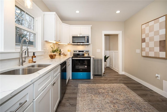 kitchen featuring white cabinets, sink, dark hardwood / wood-style floors, appliances with stainless steel finishes, and radiator heating unit