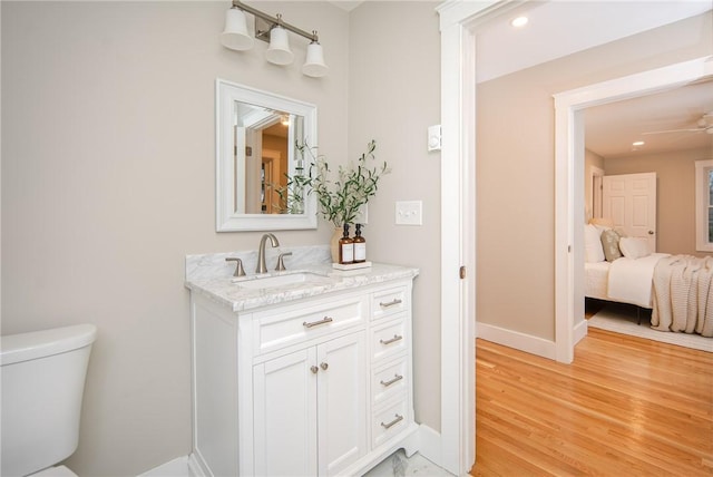 bathroom featuring ceiling fan, vanity, wood-type flooring, and toilet