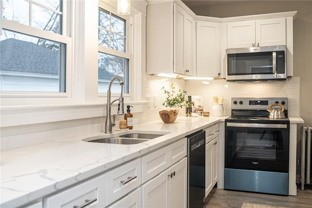 kitchen featuring appliances with stainless steel finishes, backsplash, sink, dark hardwood / wood-style floors, and white cabinetry