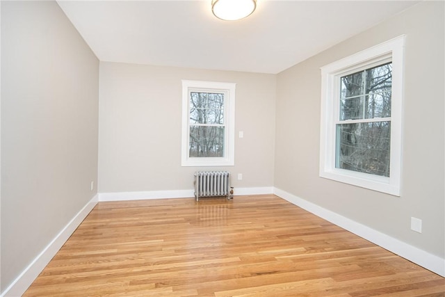 spare room featuring radiator heating unit and light wood-type flooring