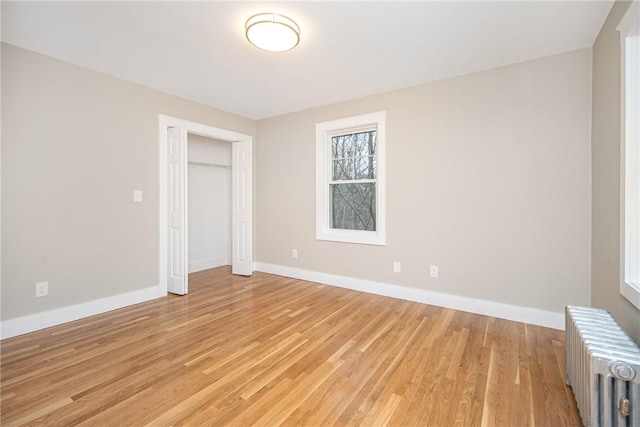 unfurnished bedroom featuring a closet, light hardwood / wood-style flooring, and radiator