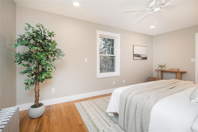 bedroom with radiator heating unit, light hardwood / wood-style flooring, and ceiling fan