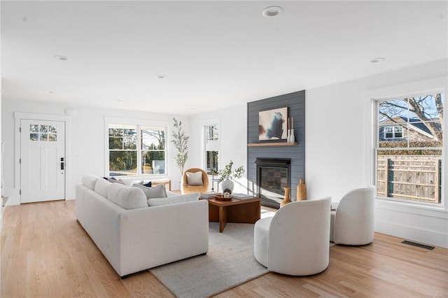 living room featuring a large fireplace and light hardwood / wood-style floors