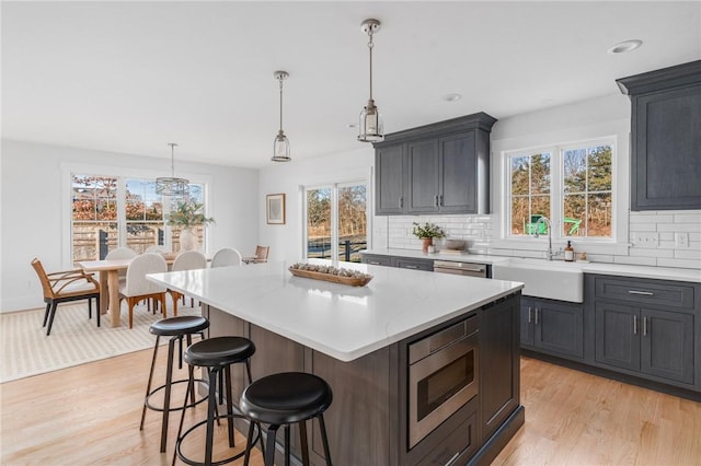 kitchen featuring tasteful backsplash, a kitchen island, stainless steel microwave, and sink